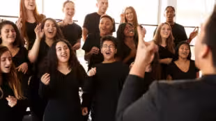 coaching vocal team building - Male And Female Students Singing In Choir With Teacher At Performing Arts School
